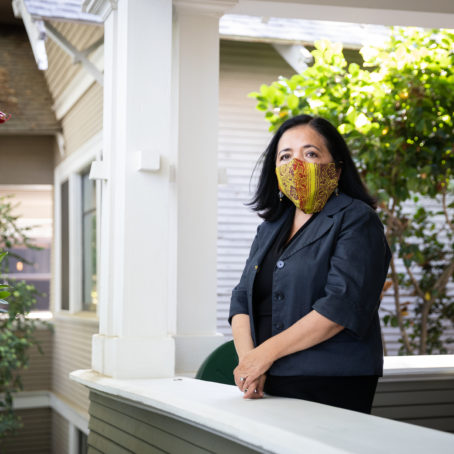 Woman wearing a protective mask, standing on her porch.