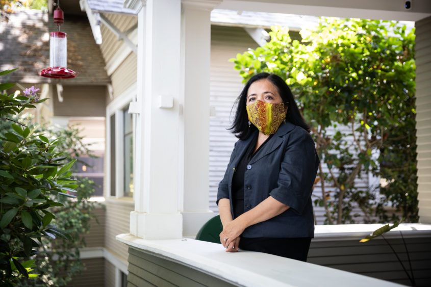 Woman wearing a protective mask, standing on her porch.