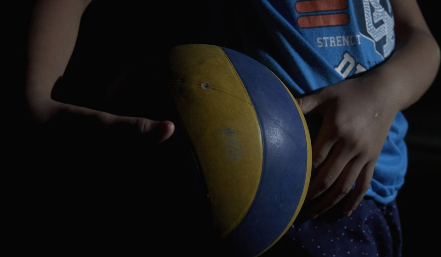A child survivor of sexual exploitation seen holding a yellow and blue volleyball
