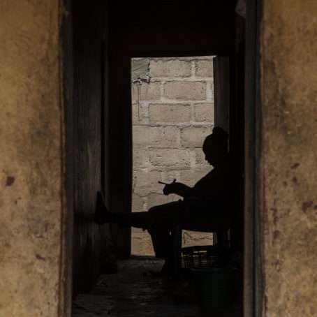 A woman sits outside her home; a silhouette of a woman