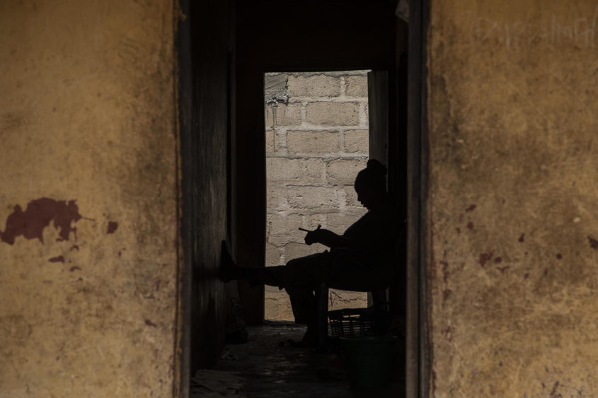 A woman sits outside her home; a silhouette of a woman