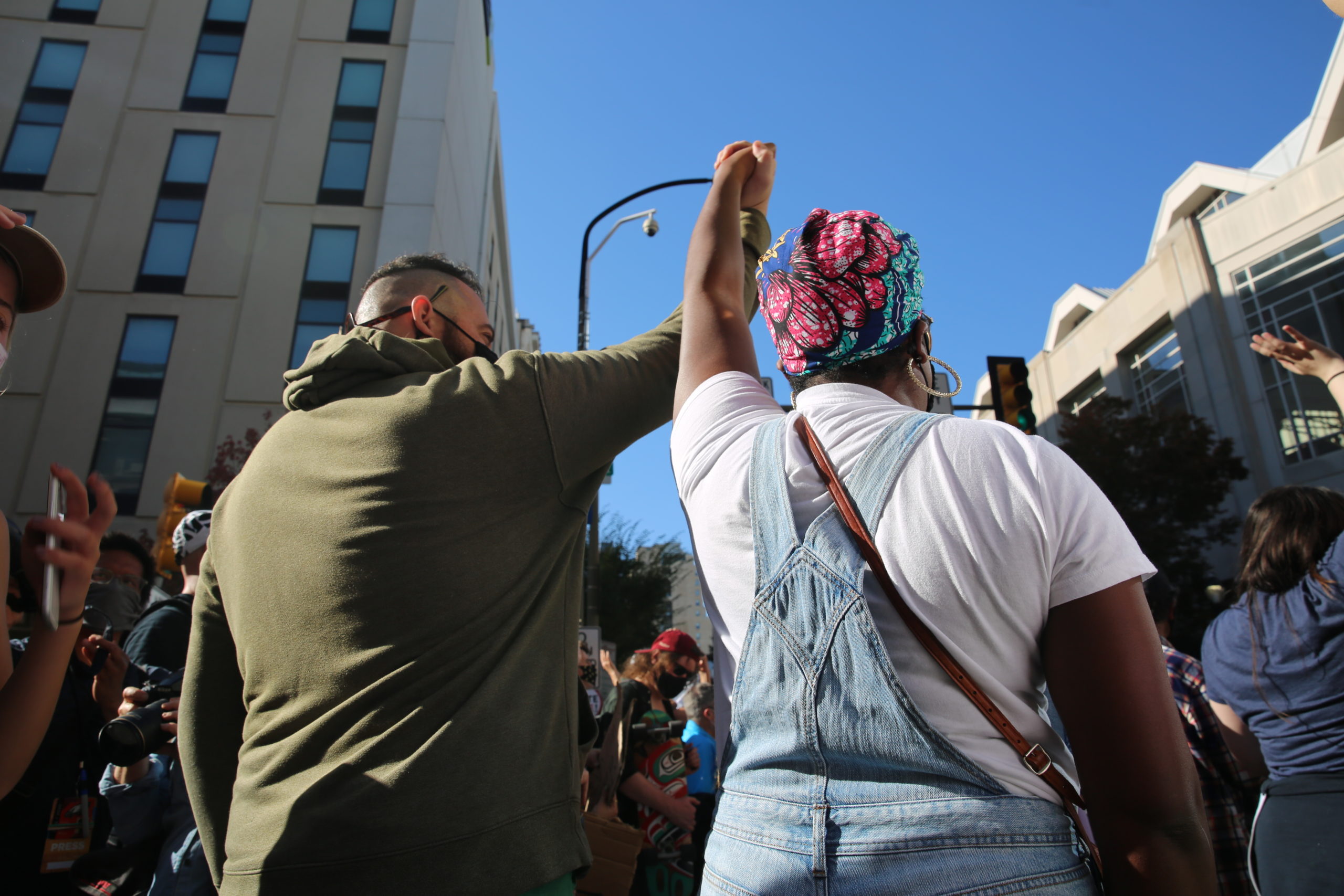 A man and woman stand in a crowd with their arms raised