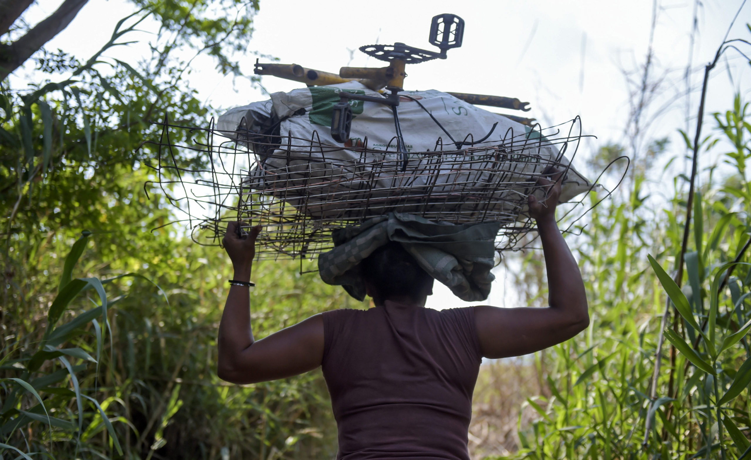 A view of a woman carrying scrap metal on her head