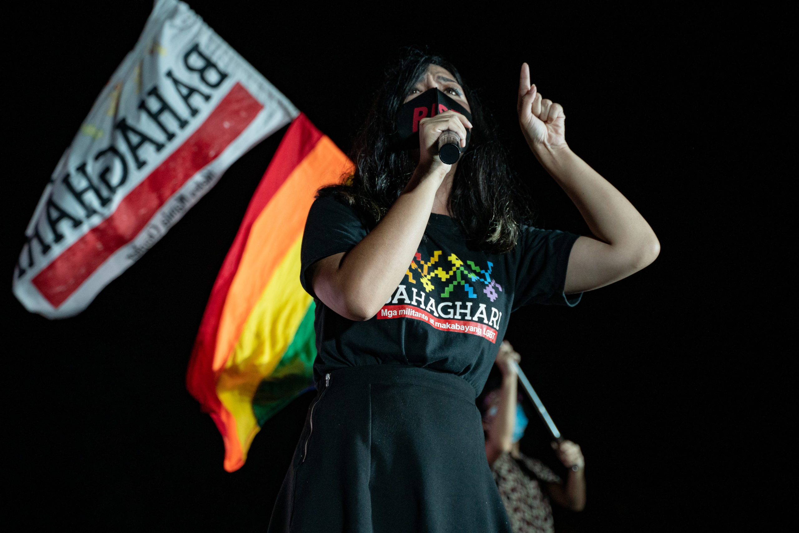 Photo of a woman giving a speech with flags in the background