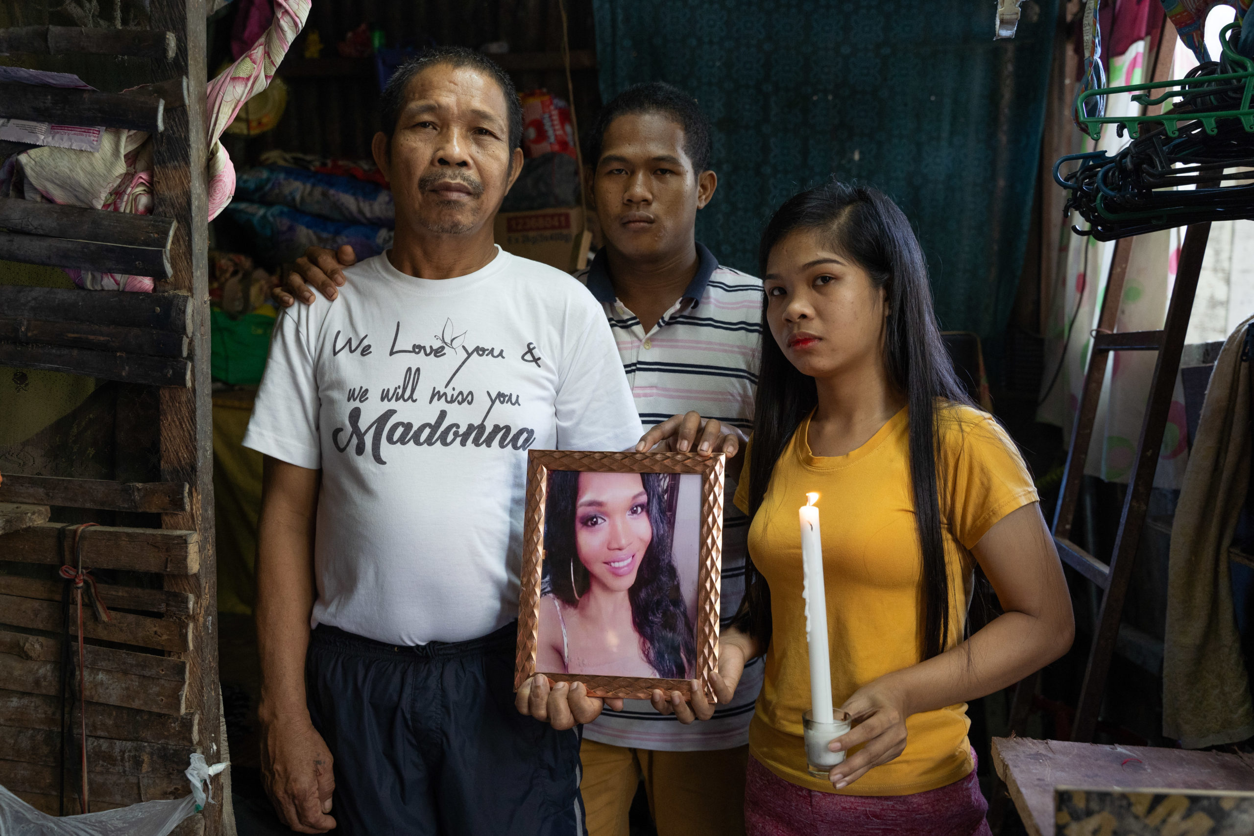 Three people hold a framed photo and a lit candle