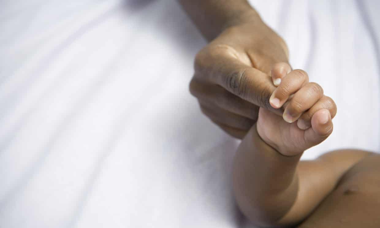 A photo of a baby holding a woman's finger