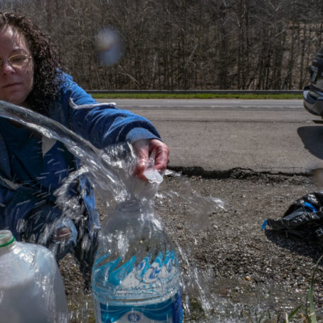 A photo of a woman filling up jugs of water from a water pump