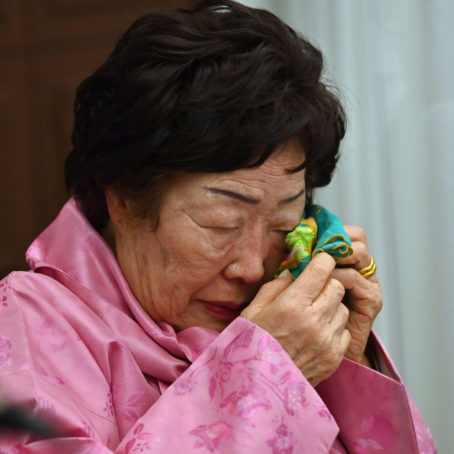 A photograph of a woman crying, with a handkerchief at her eye