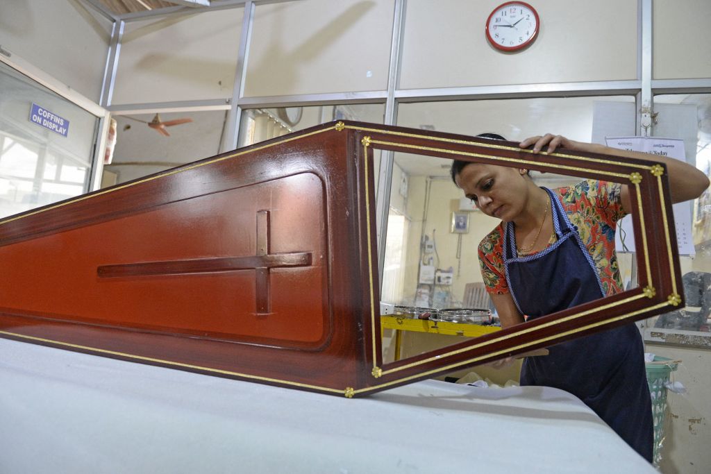 A photo of a woman worker holding the lid to a coffin