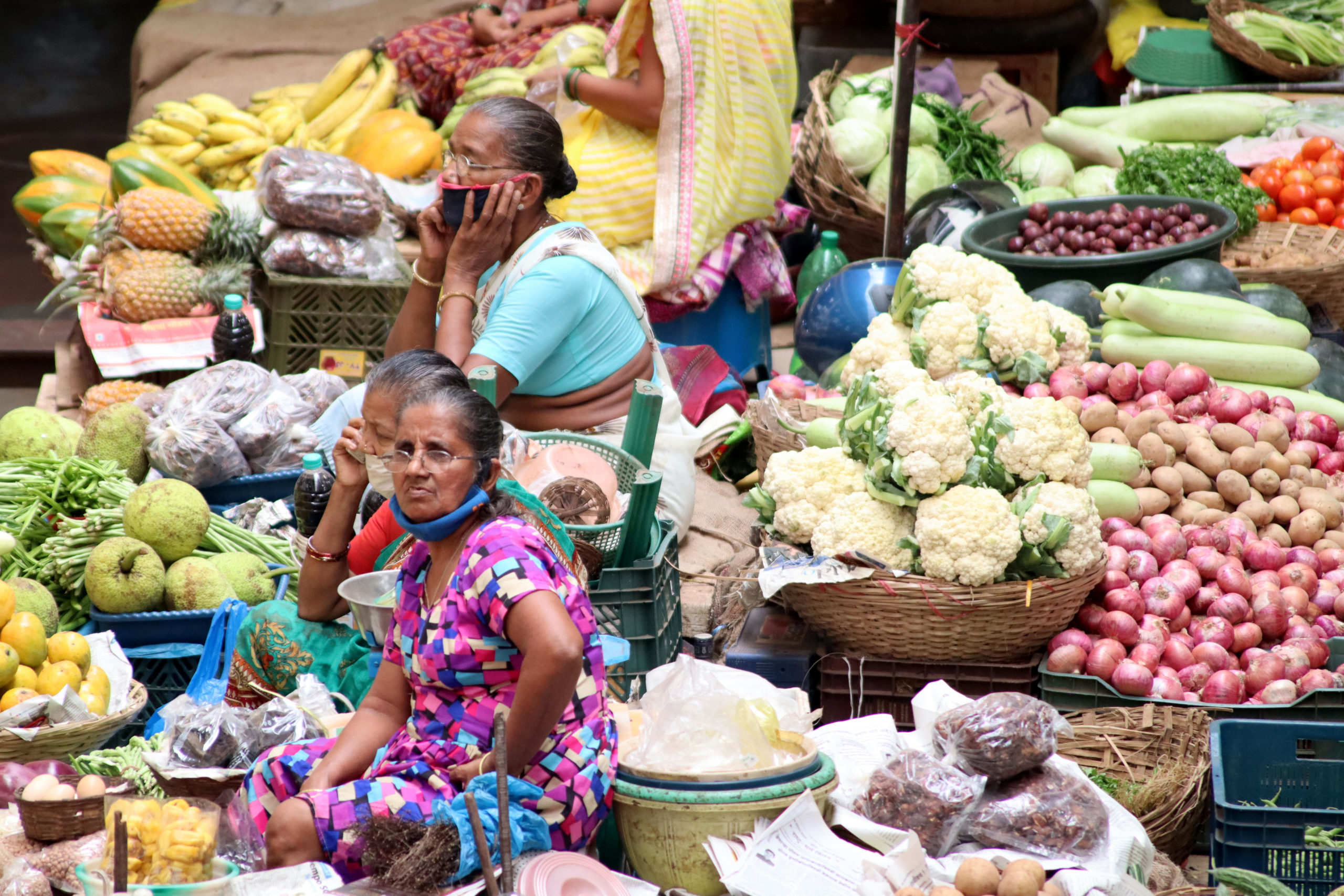 Three women vendors seated at a fruit market