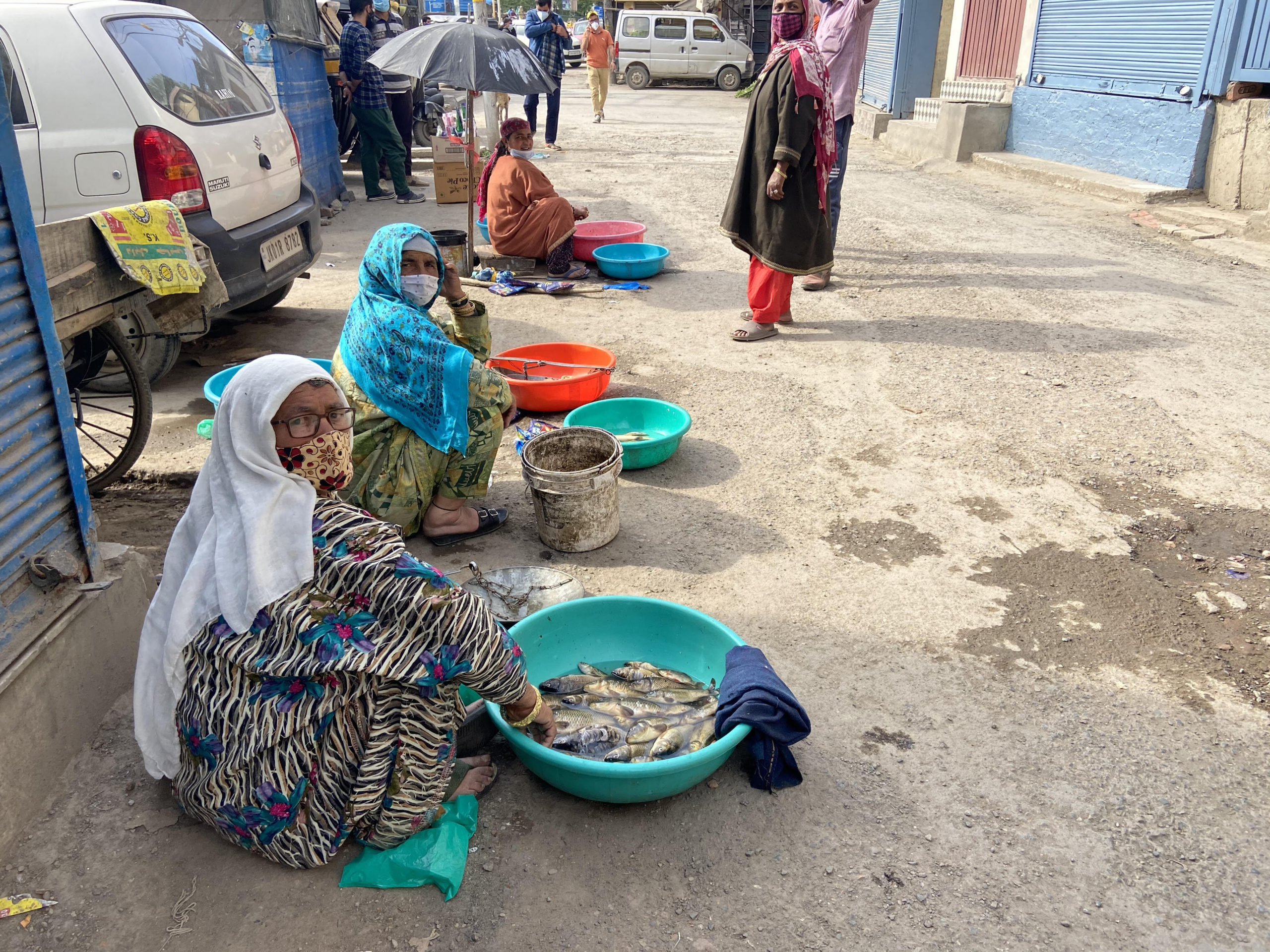A photo of three Indian women selling fish