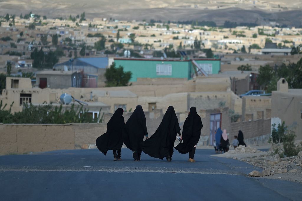 A photo of four women in burkas walking down a road