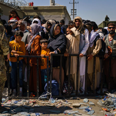 Photo of a packed crowd behind a temporary fence with liter on the ground