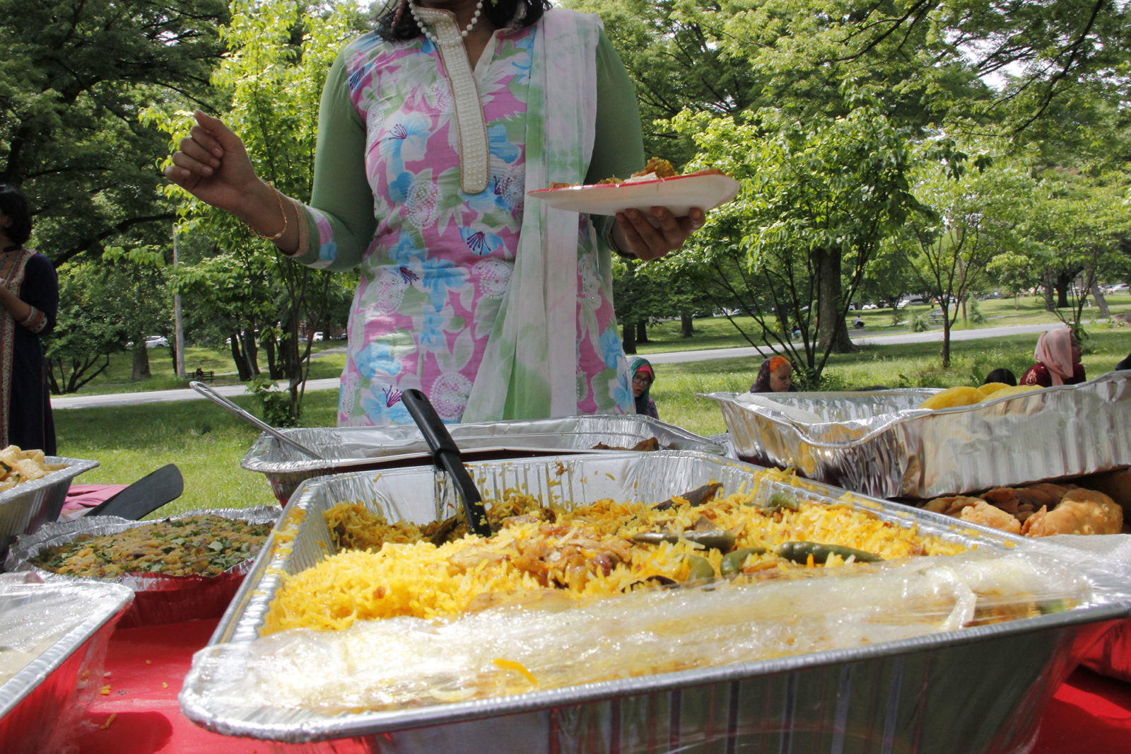 A photo of a woman at selecting food at an outdoor gathering