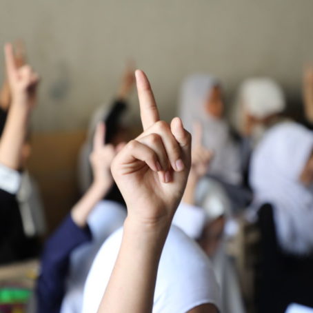 A photo of students raising their hands in a classroom