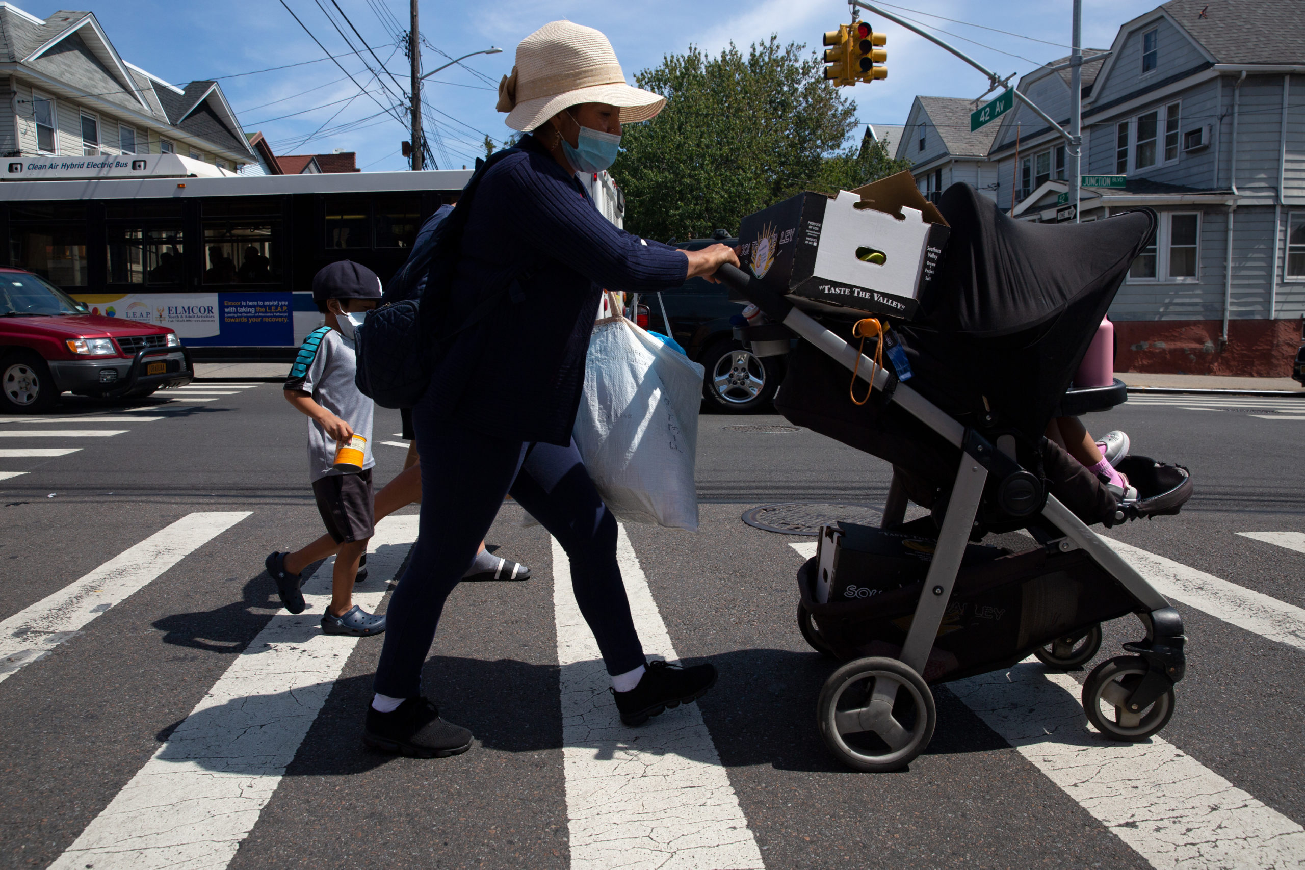 Woman pushing a stroller after picking up food from a food bank in Corona, Queens, 2021