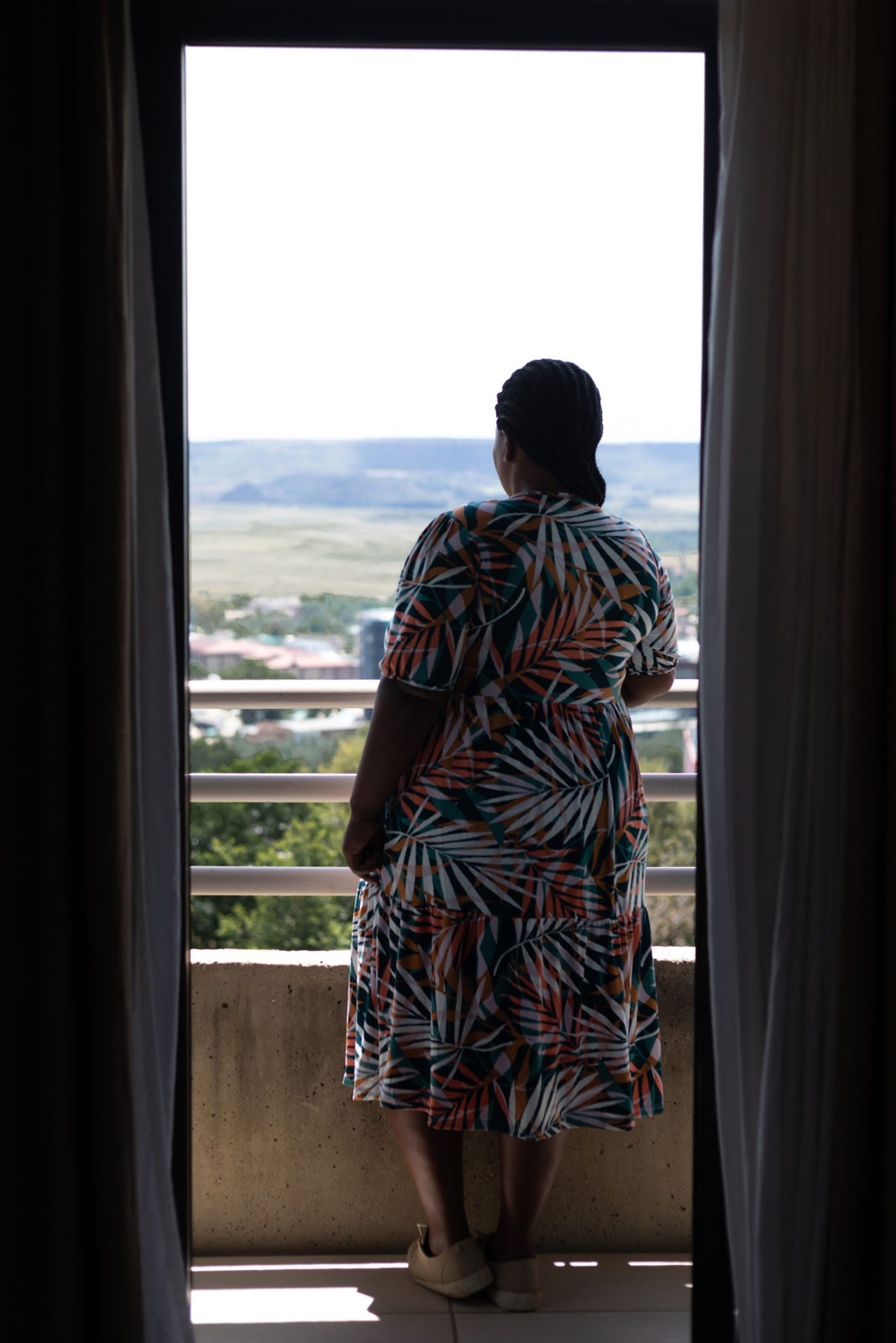 A photo of the back of a woman looking out at a balcony