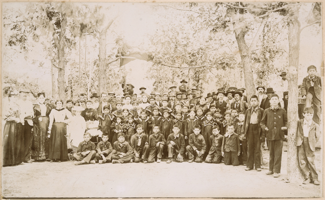 A black and white photo of a group of students and teachers posing for a photo outside
