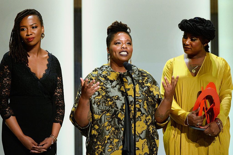 A photo of three women standing behind a mic