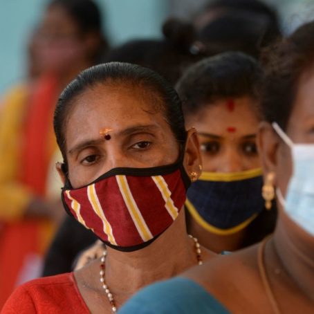 Photo fo women standing in line wearing protective face masks