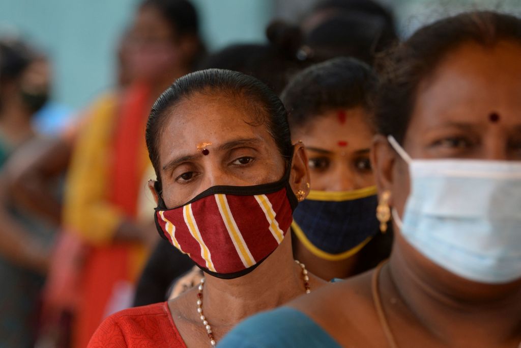 Photo fo women standing in line wearing protective face masks