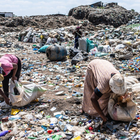 A photo of two women picking up trash at a dumpsite