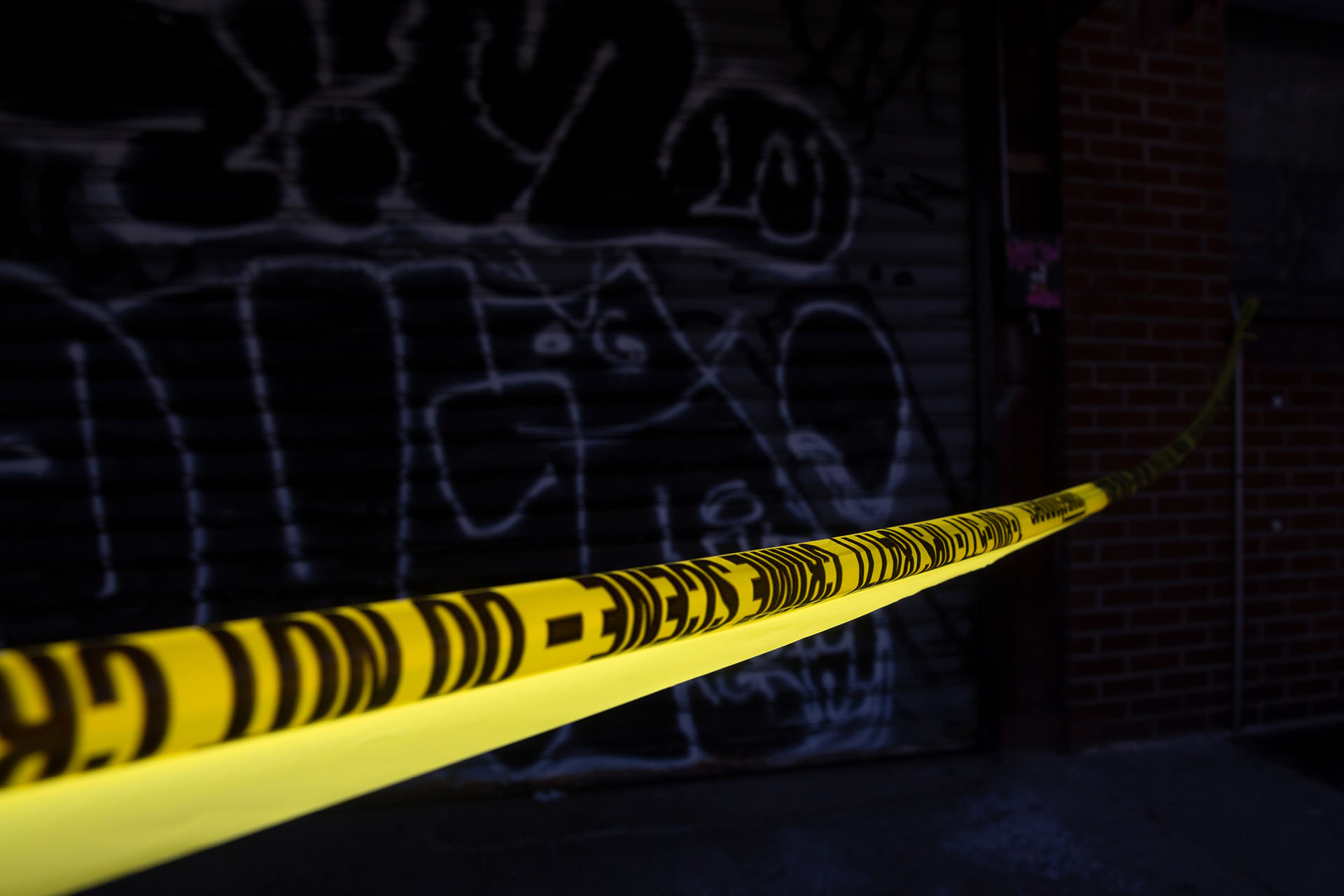 A photo of police tape with a wall covered in graffiti