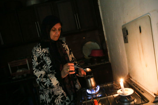 A photo of a woman heating water over a stove