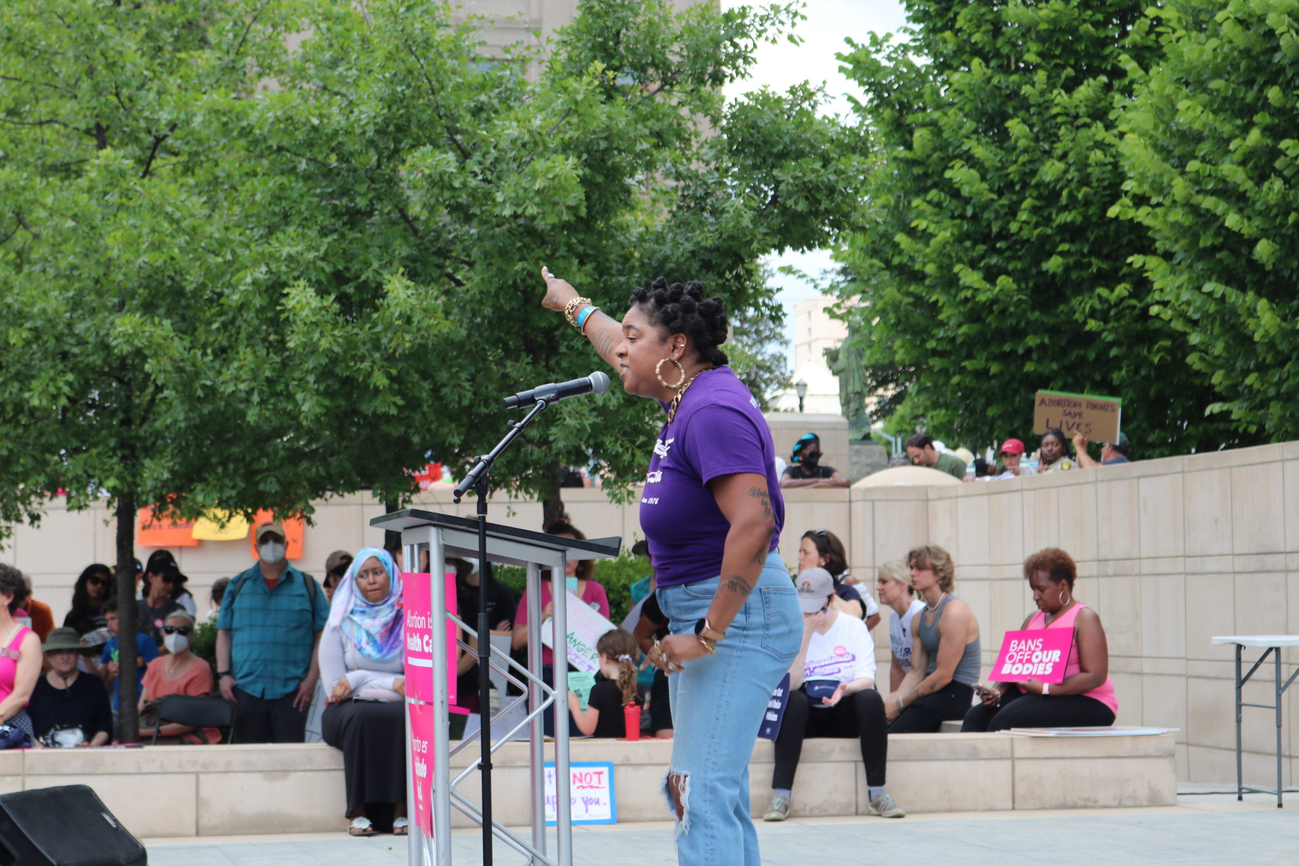 A woman stands at a podium and points at the Georgia statehouse building.