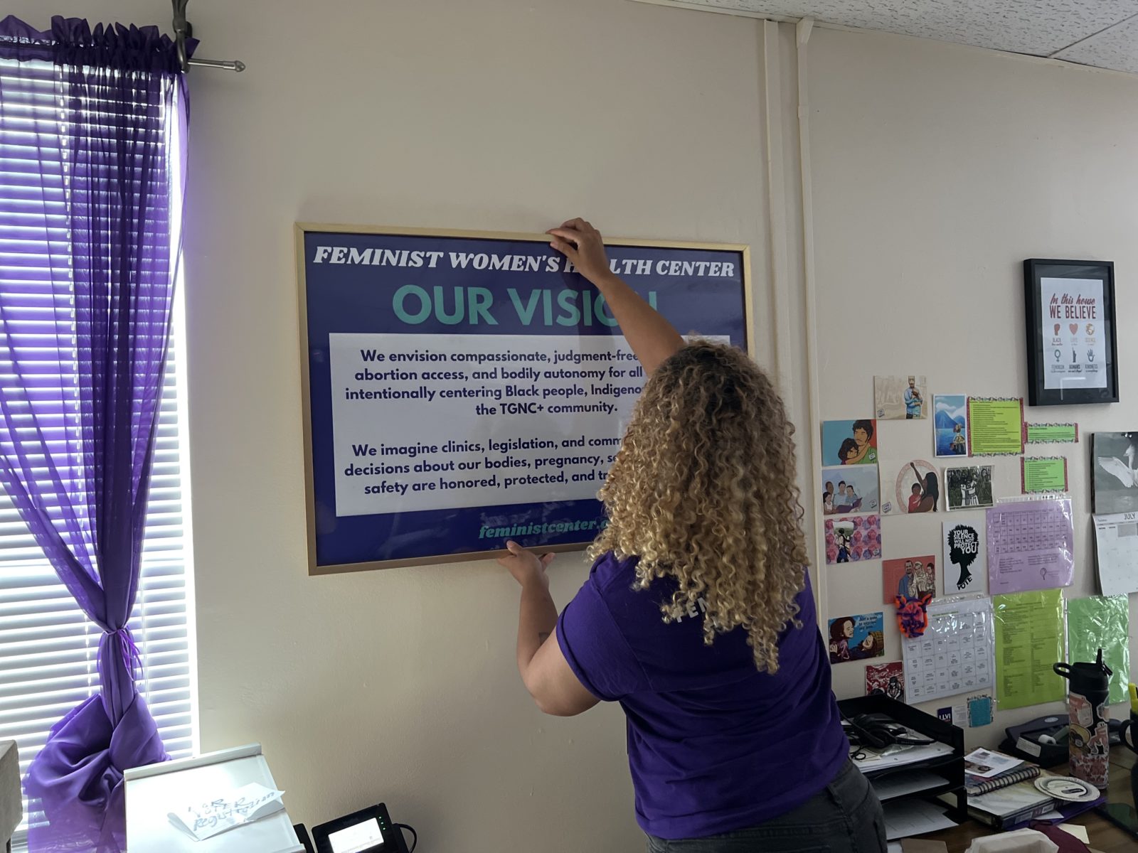 MK Anderson, A woman at Feminist Women’s Health Center hangs a new sign on a wall in the clinic’s call center.