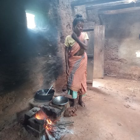 A woman stands in her kitchen next to food cooking over a fire