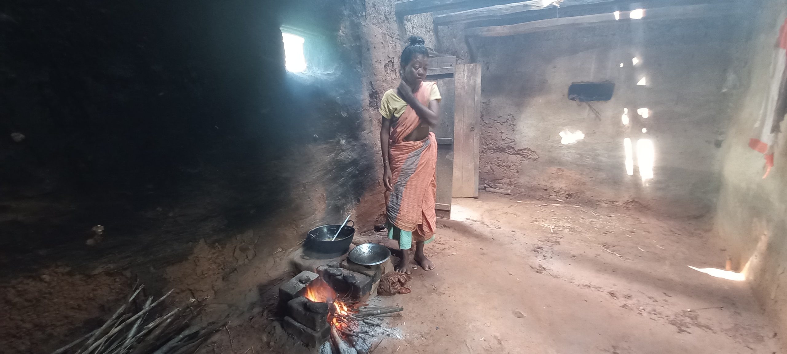 A woman stands in her kitchen next to food cooking over a fire