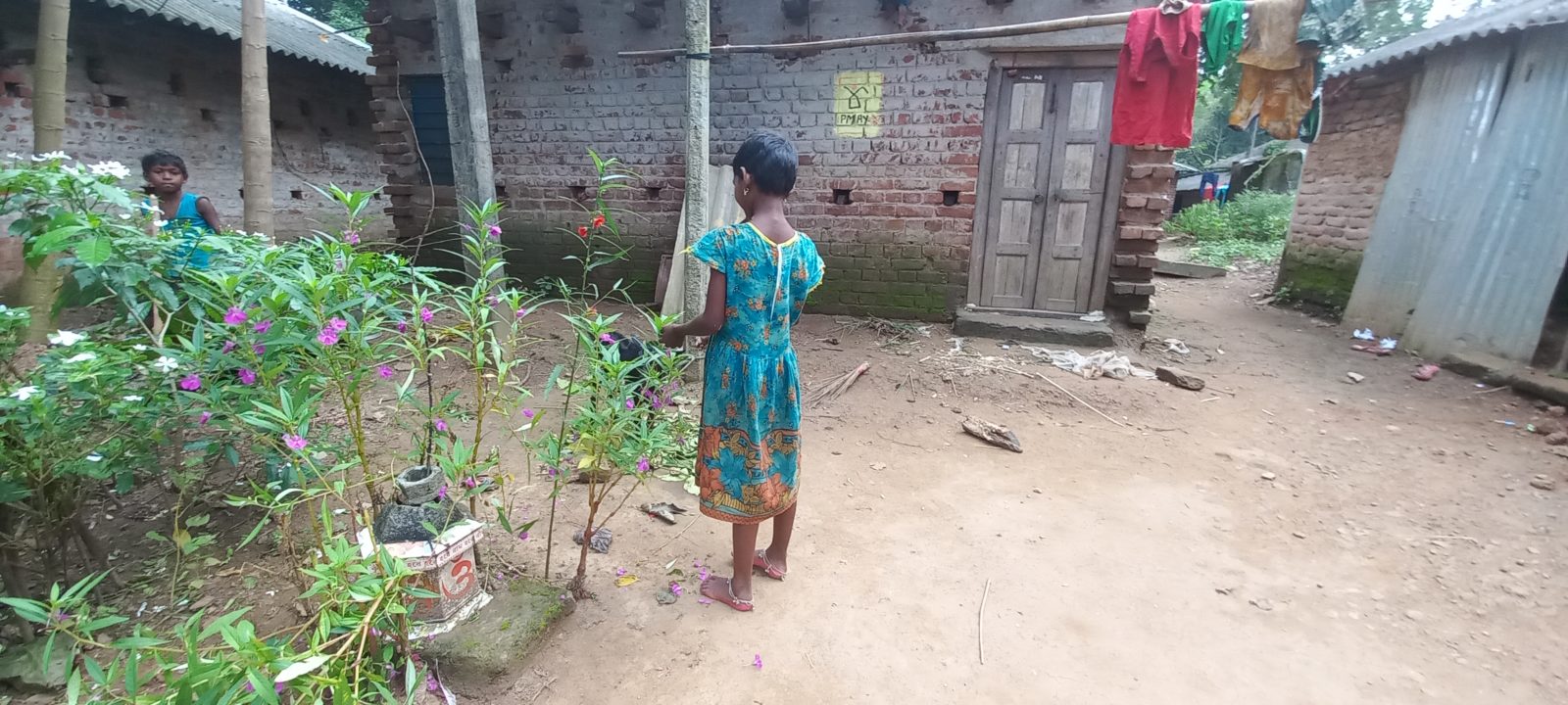 A young girl stands next to plants picking them.