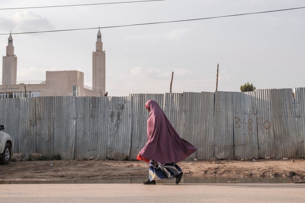 A woman walks past a wooden fence in Somaliland